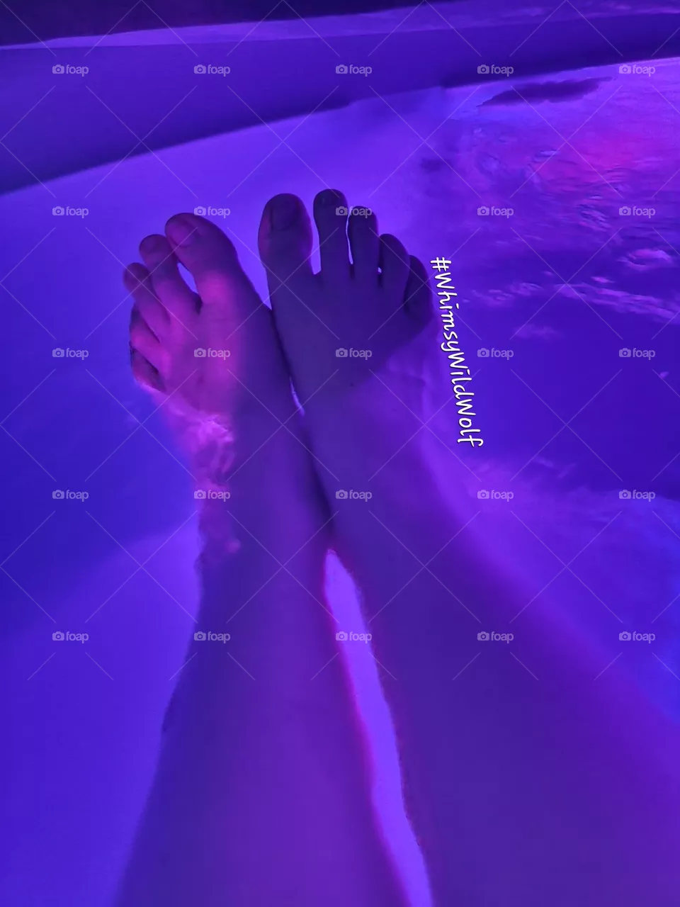 Feet relaxing in a hot tub after a long day, enjoying the soft purple glow.
