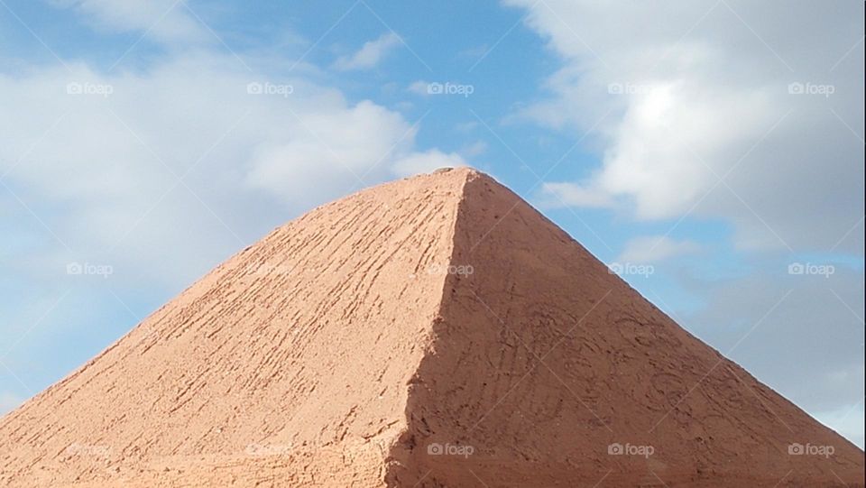 The shape of a pyramid hugs the blue of the sky.