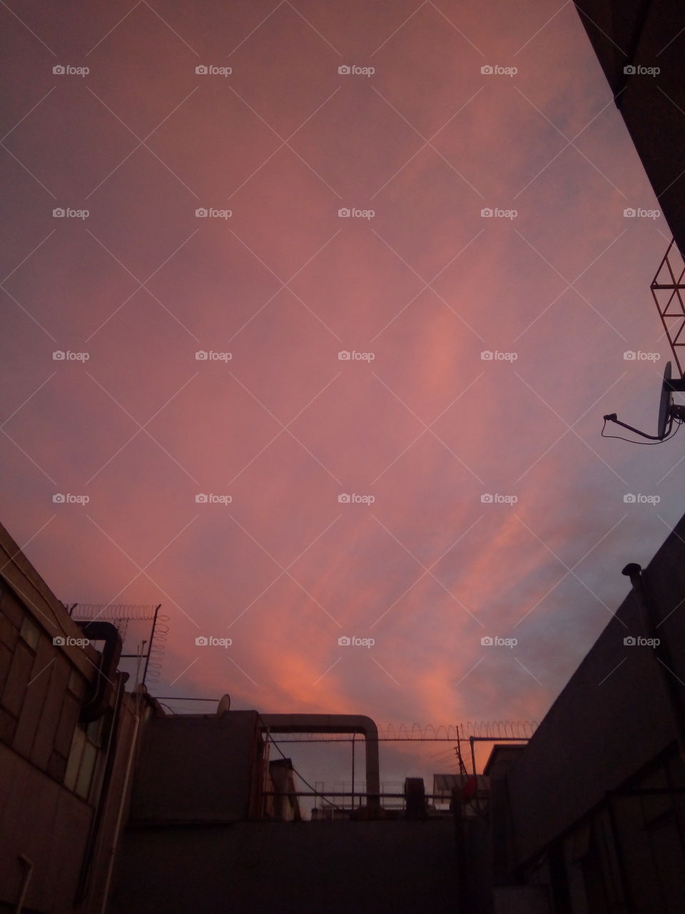 foto del cielo en un atardecer en la CDMX tomada desde la ventana de un edificio. el cielo con las nubes y el atardecer hacen un efecto de color rojizo.
