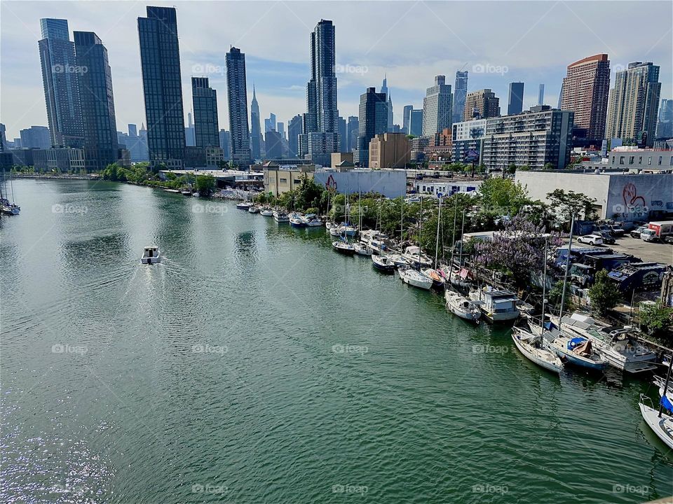 This is a beautiful panoramic view of “Newtown Creek” from the “Pulaski Bridge” that connects LIC, Queens to “Greenpoint”, Bklyn. Across the “East River” we see “Manhattan” including the “Empire State Building”. 2024. Hypnotic Productions