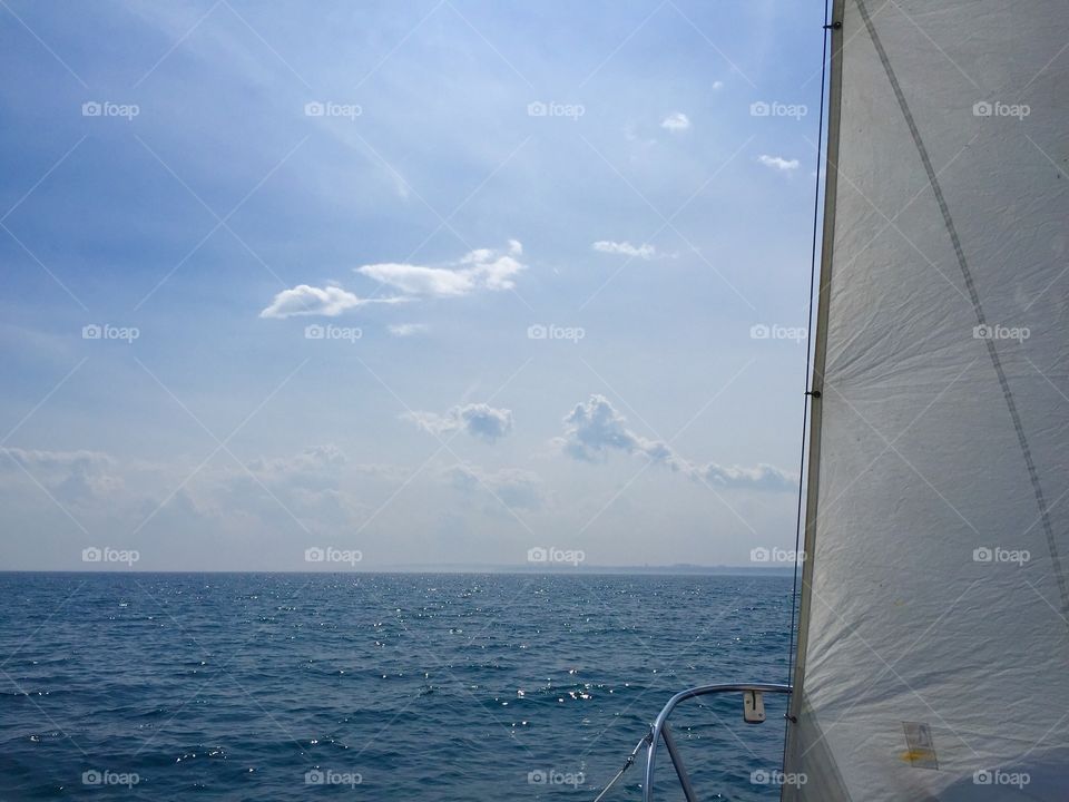 Sailboat  with white sail sailing on lake on the horizon close up 
