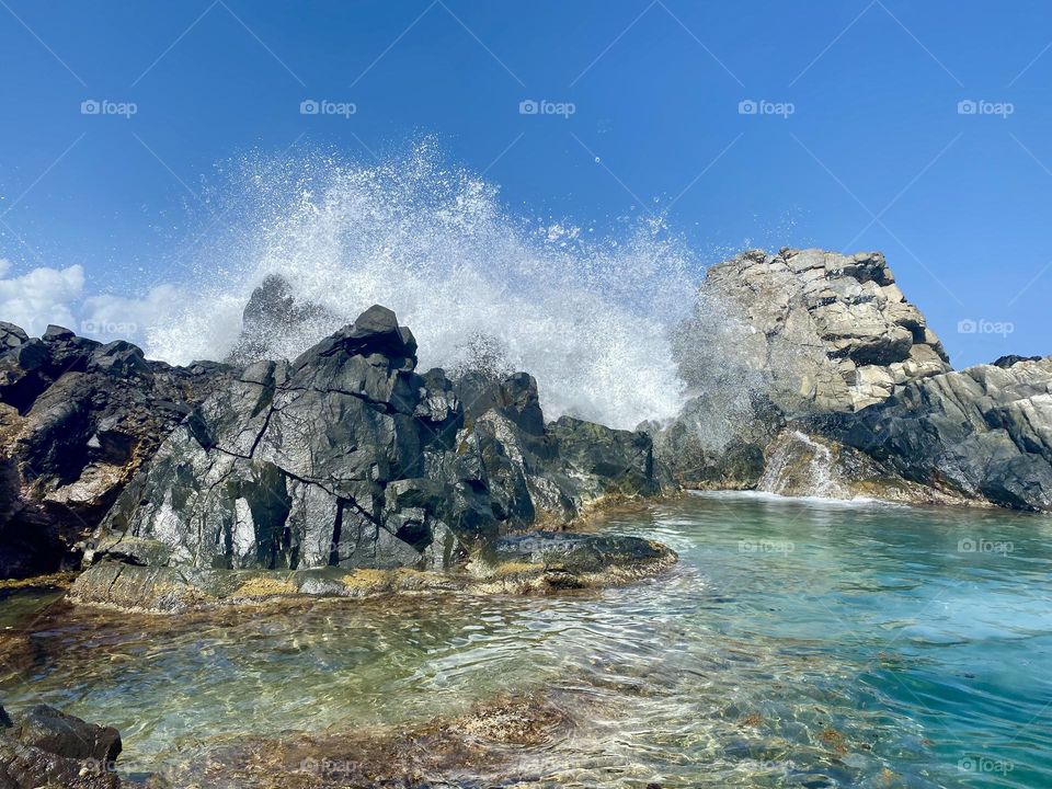 Waves crashing over rocks creating a natural pool