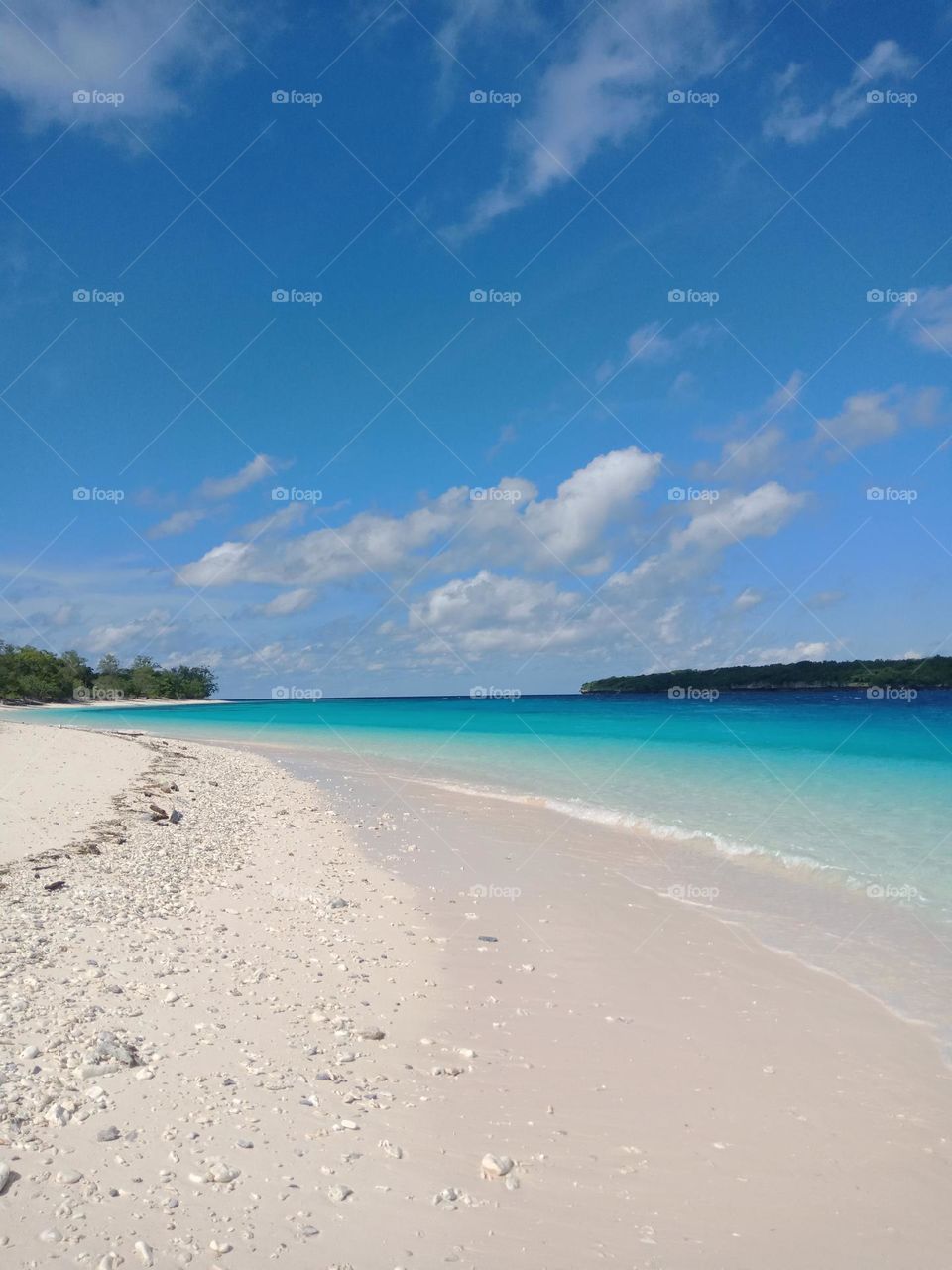 Jaco island beach, beautiful sunny day with clear blue water, a paradise island. White sand with shells. View of the coast and the island