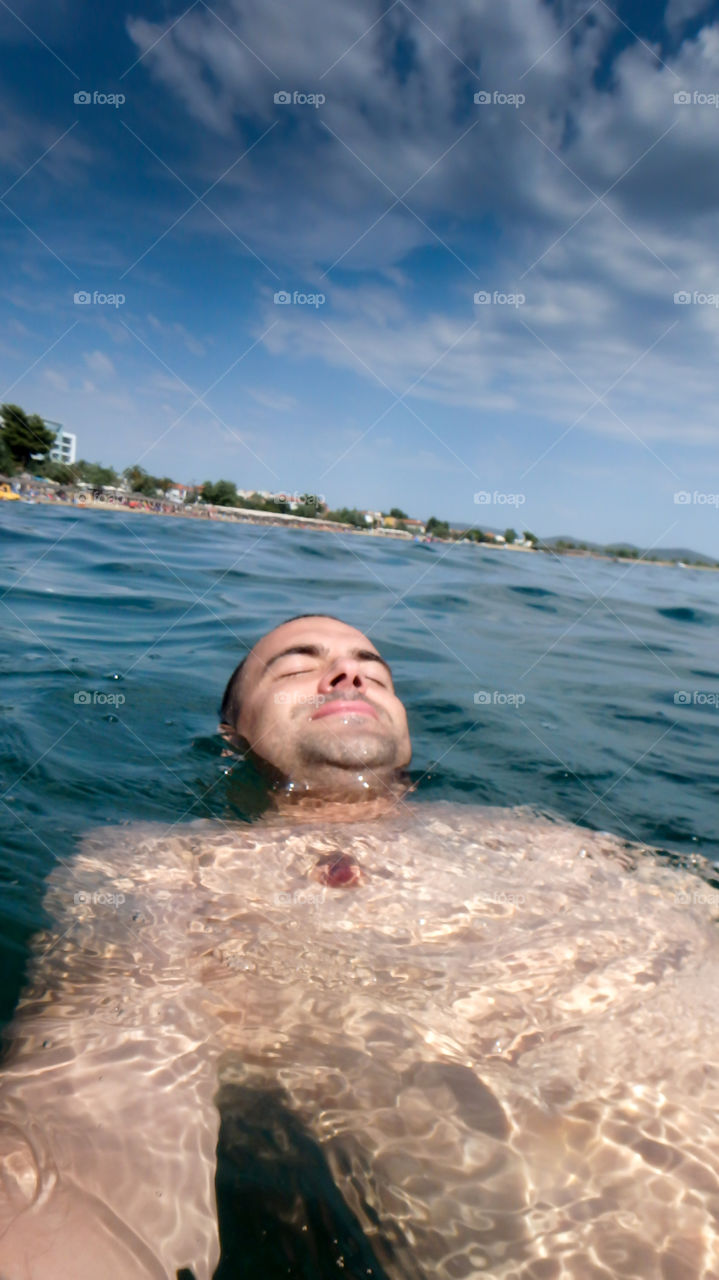 Man diving, man underwater smiling and relaxing in big blue sea