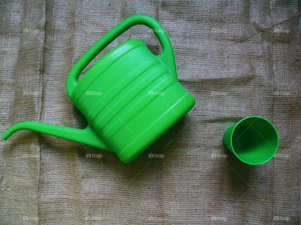 Green glass and green watering can for watering flowers