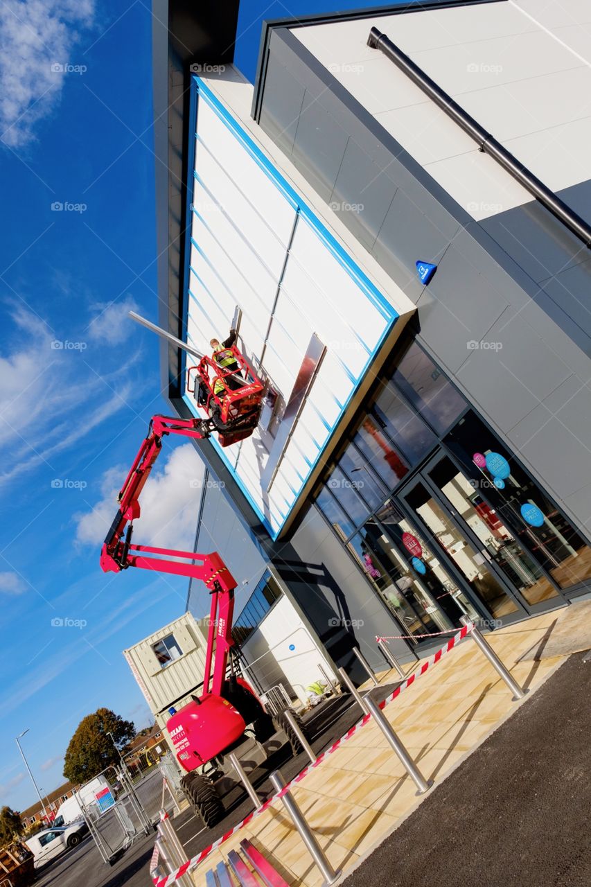 Red cherry picker against my dean store building with slanted angle