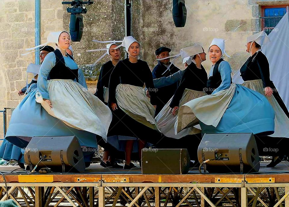 Women dressed in Breton traditional costumes dancing on stage at the Embroiderers Festival in Pont l'Abbé