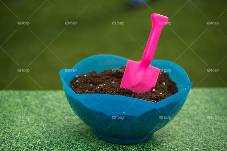 Pink garden tool in soil isolated on green background