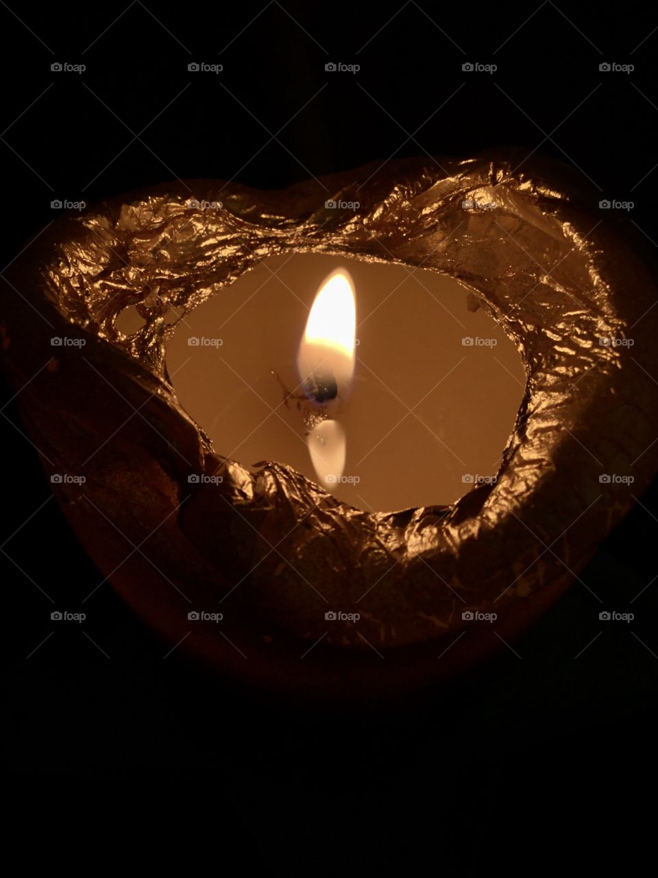 Beauty of the night - A lighted candle wick reflects on the surface of the melted wax 