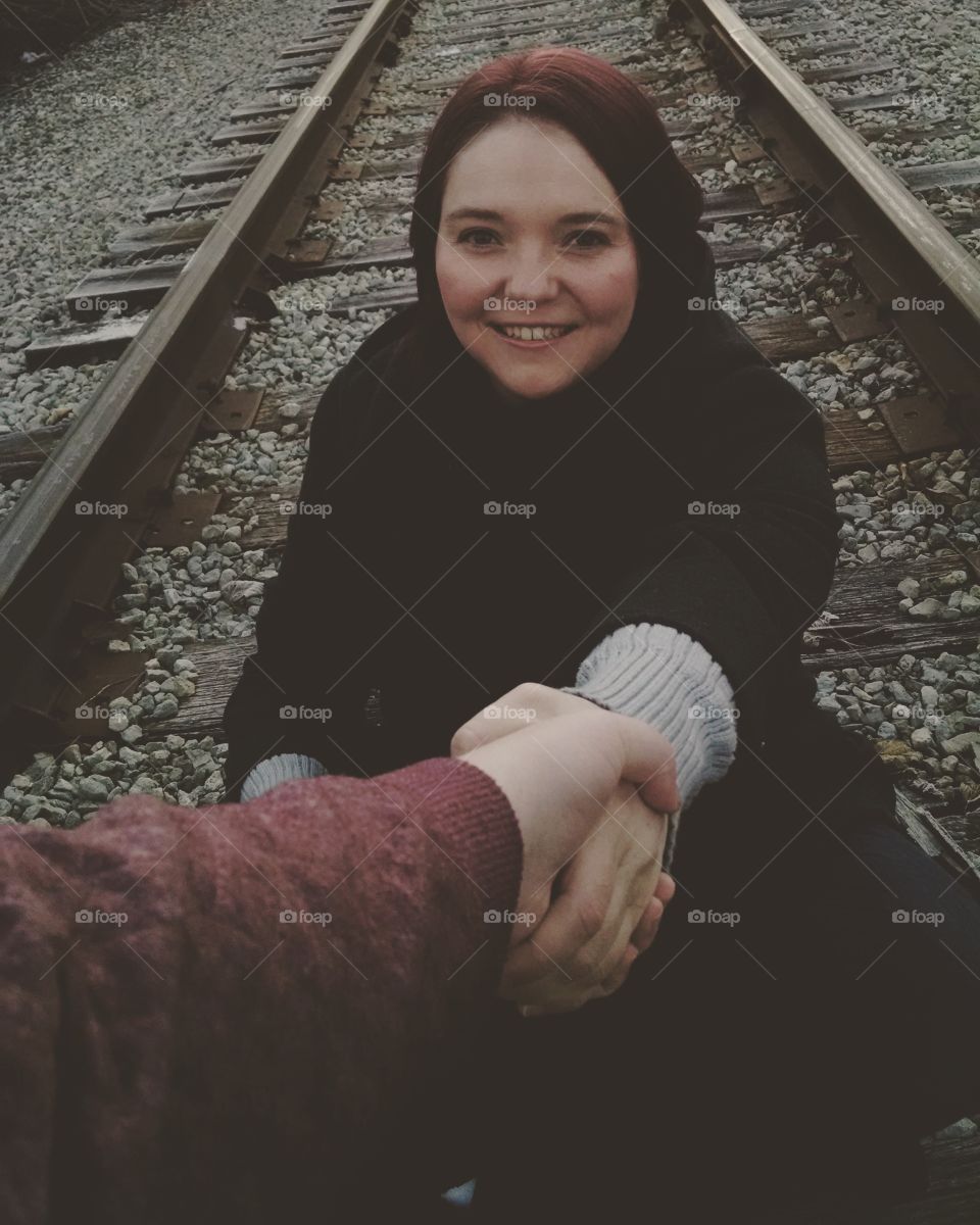 Person holding woman hand on railroad