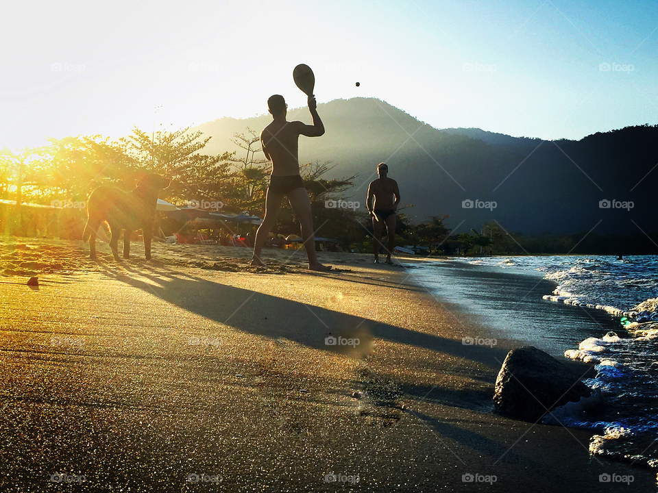 The "frescoball" players . In Paraty two guys play a popular game in the Brazilian beaches while their dog watches the ball going and coming. 