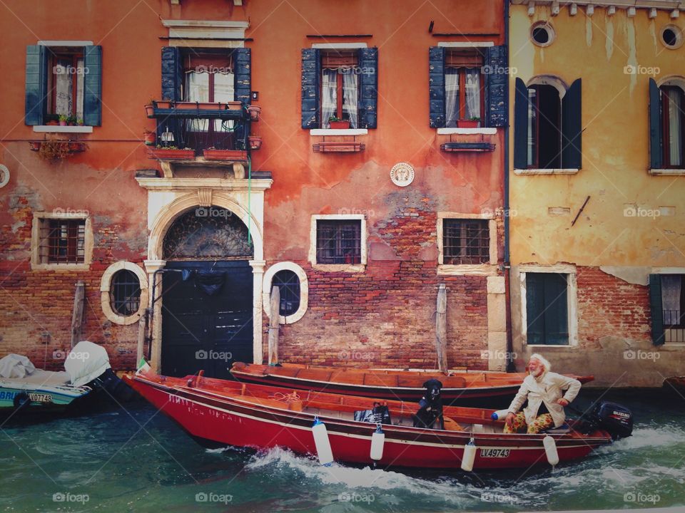 Man with his dog friend, enjoying the walk down the canal in Venice. Colors of streets in Venice. 