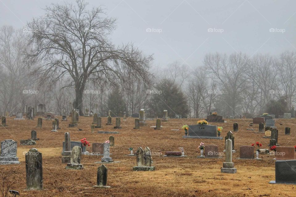 Old cemetery with headstones on a cold, foggy winter morning.