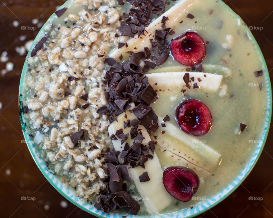 Full frame closeup of healthy fruit smoothie bowl with dark antioxidant rich chocolate, cherries, banana, granola, coconut, chia seed artisanal healthy food photography