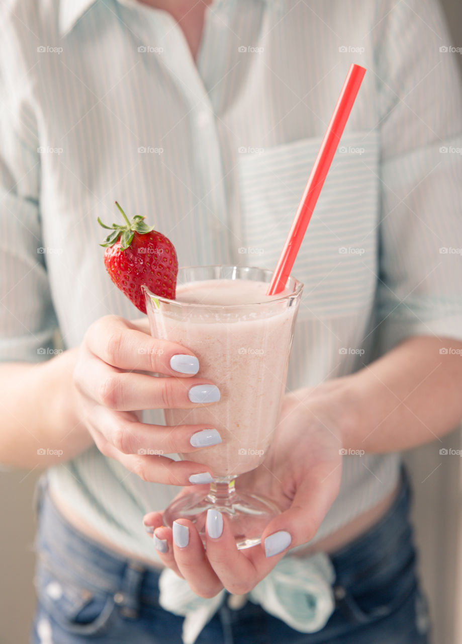 A fashionable young girl holding a fruity, strawberry smoothie