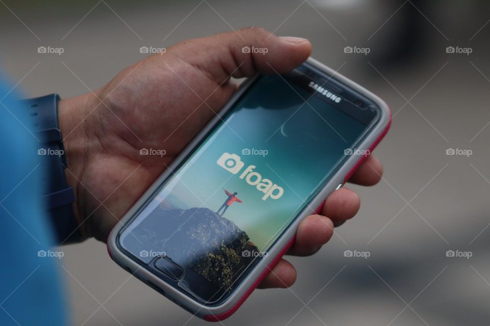 Hand is holding a smartphone with foap app on it