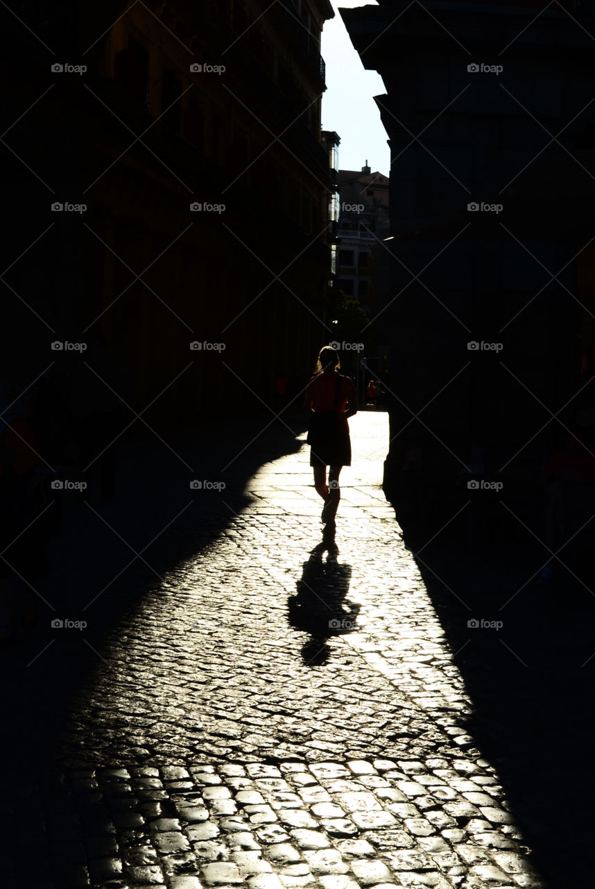 Silhouette of a woman walking through an archway 