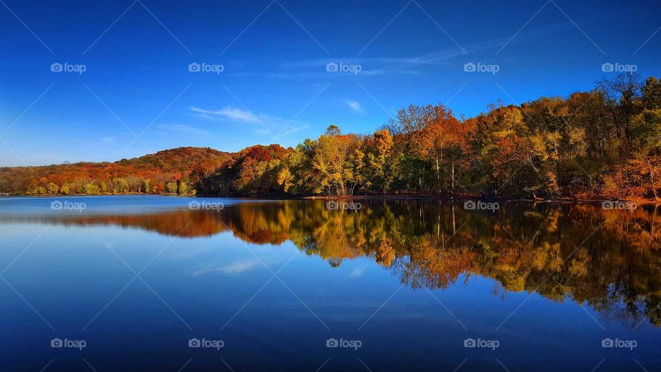 Blue sky and autumn trees reflecting on lake