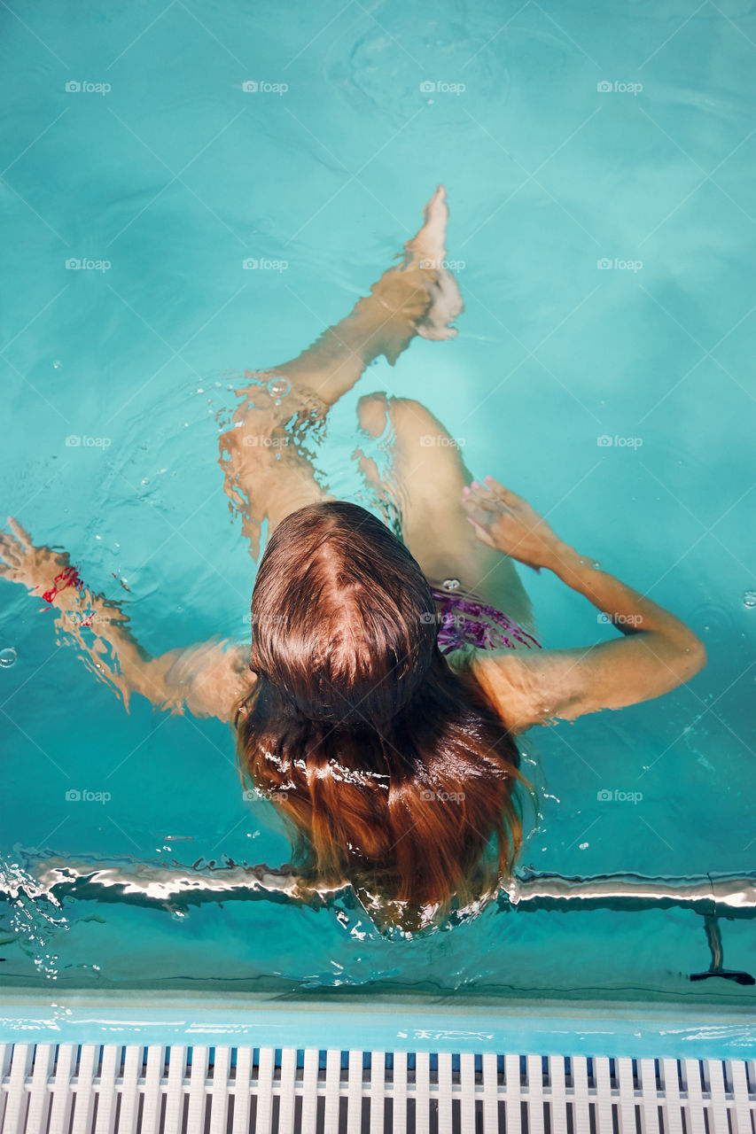 Young woman swimming and relaxing in swimming pool. Candid people, real moments, authentic situations