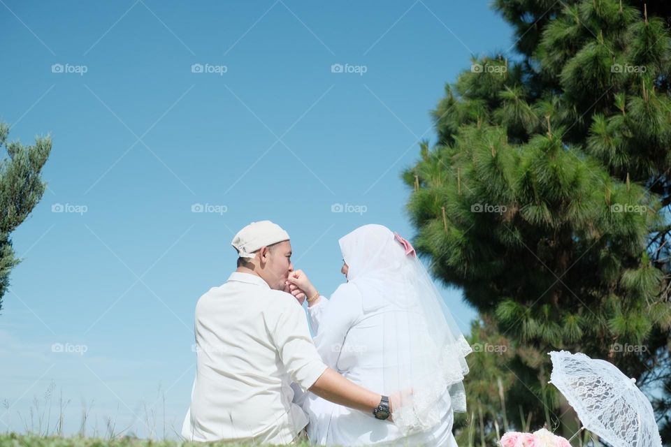 couples of newly weds wearing all white for an outdoor photoshoot.