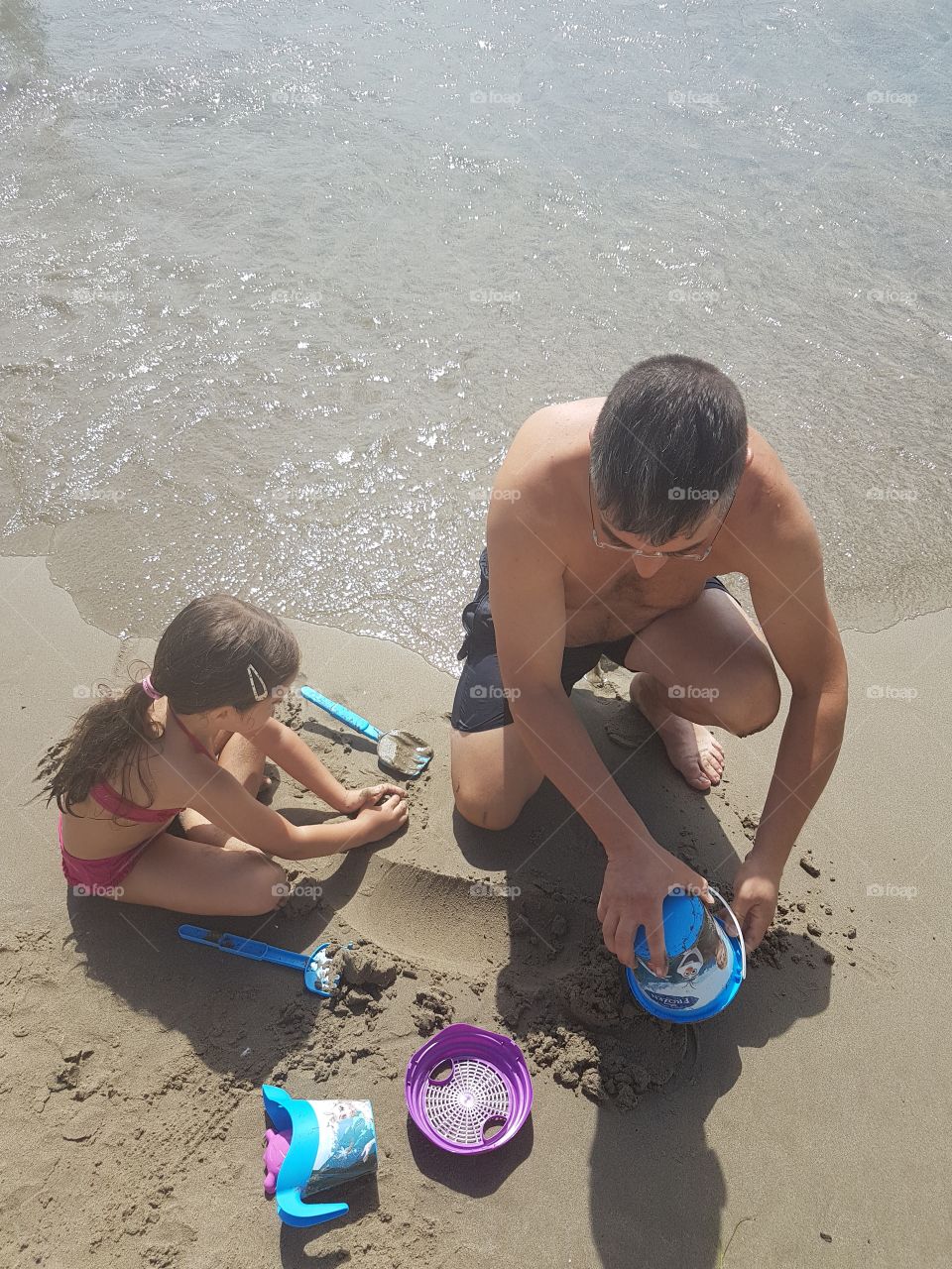 Father and daughter who have fun playing at the beach in summer