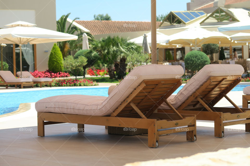Hotel pool wooden deck chairs. Sunbeds by an open air pool at a luxury hotel resort in Halkidiki Greece.