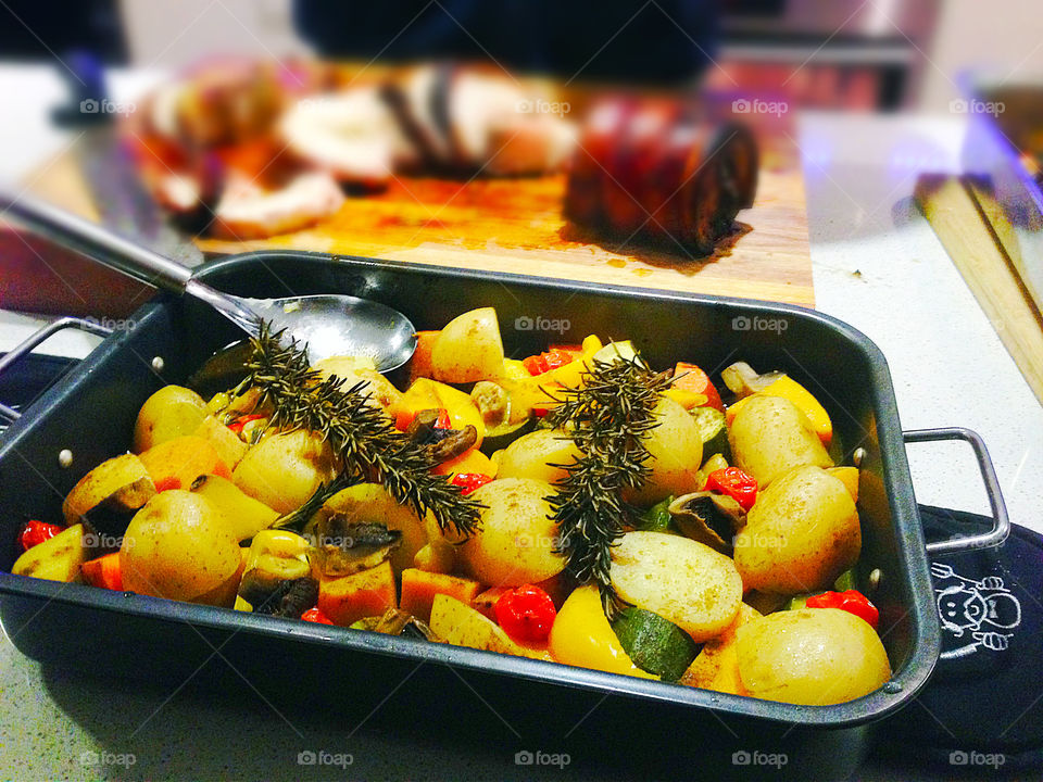 Roasted Rosemary potatoes and zucchini closeup in pan with fresh sprig Rosemary 