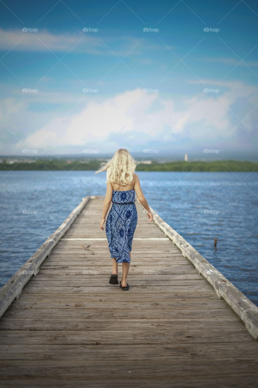 Beautiful blonde walking down the pier overlooking the gorgeous cityscape 