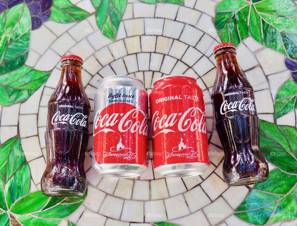 Coca Cola bottles and cans on garden table.