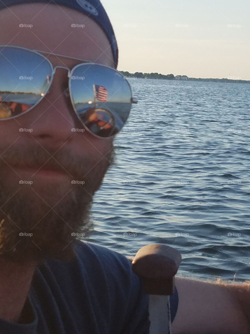 Man boating in Northern Michigan lake on Independance Day with American  flag reflected in sunglasses