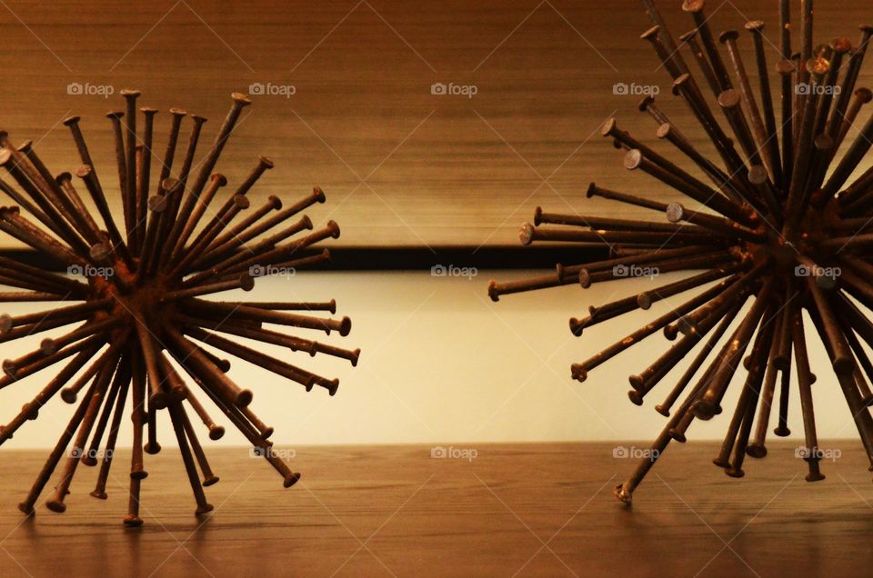An art piece of metal rustic nails in the shape of a spherical sculpture rest on top of a bedroom dresser.