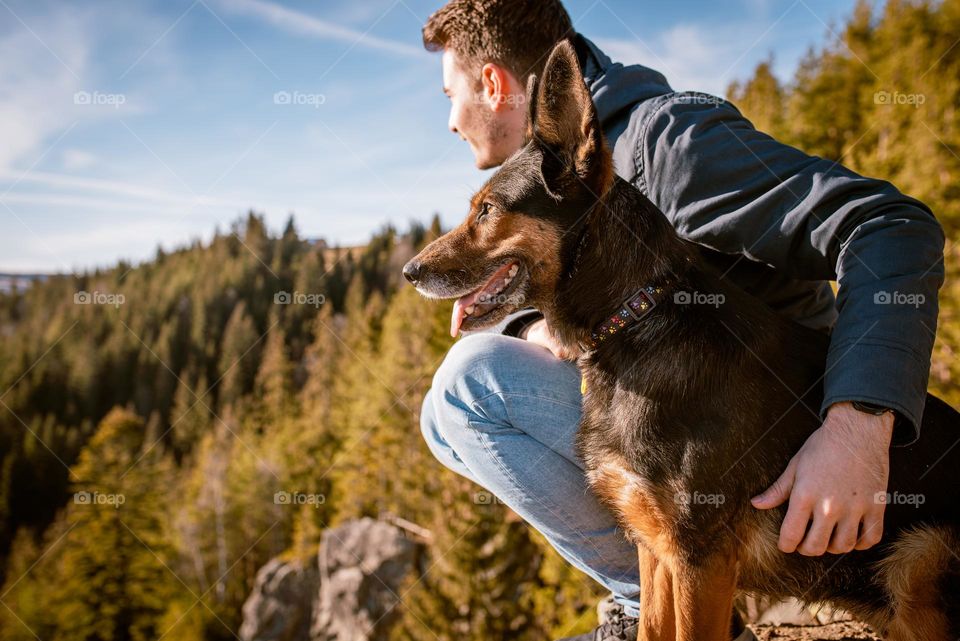 Man on a hike with his dog admiring the view over a cliff