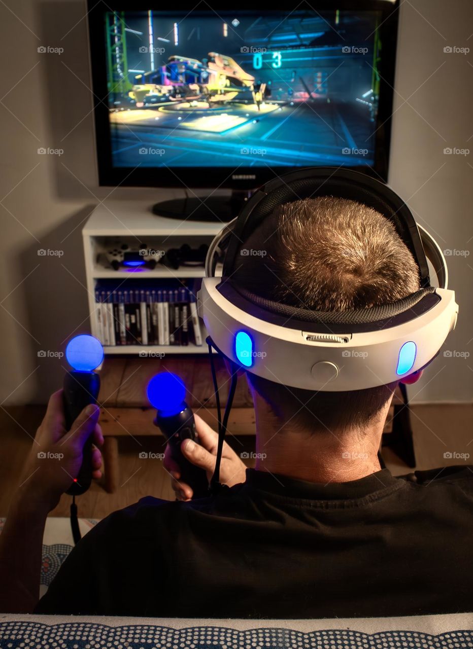 A man playing a virtual reality game, with head set & VR controllers 
