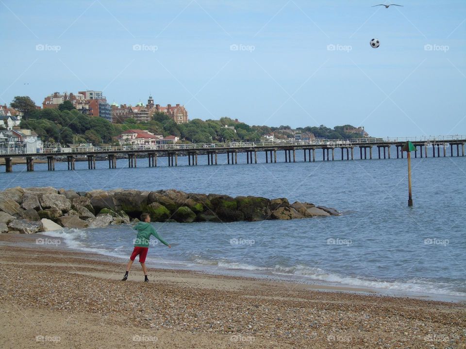 Boy playing football on the beach, Felixstowe, UK