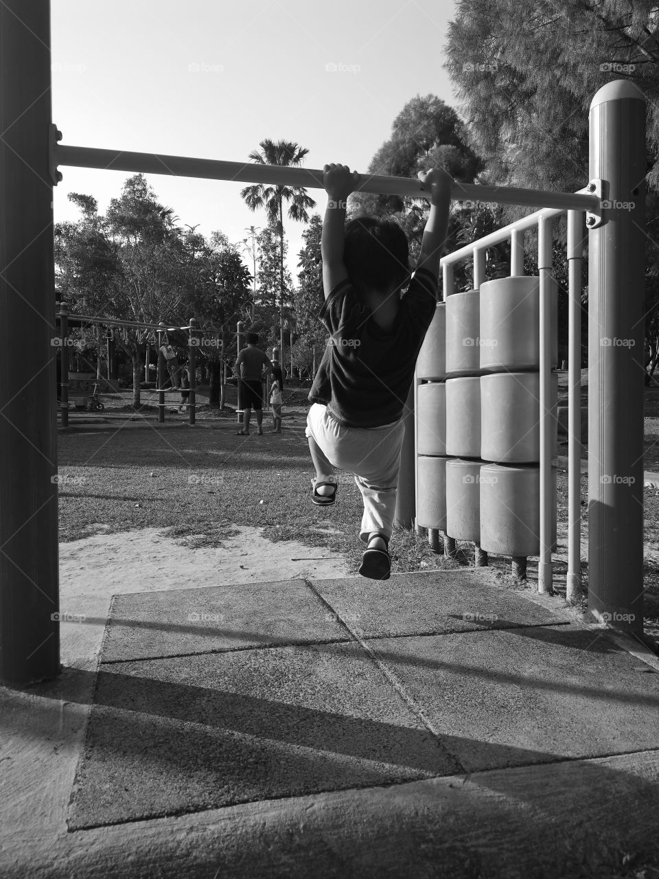 My son play hanging on a steel bar at a playground