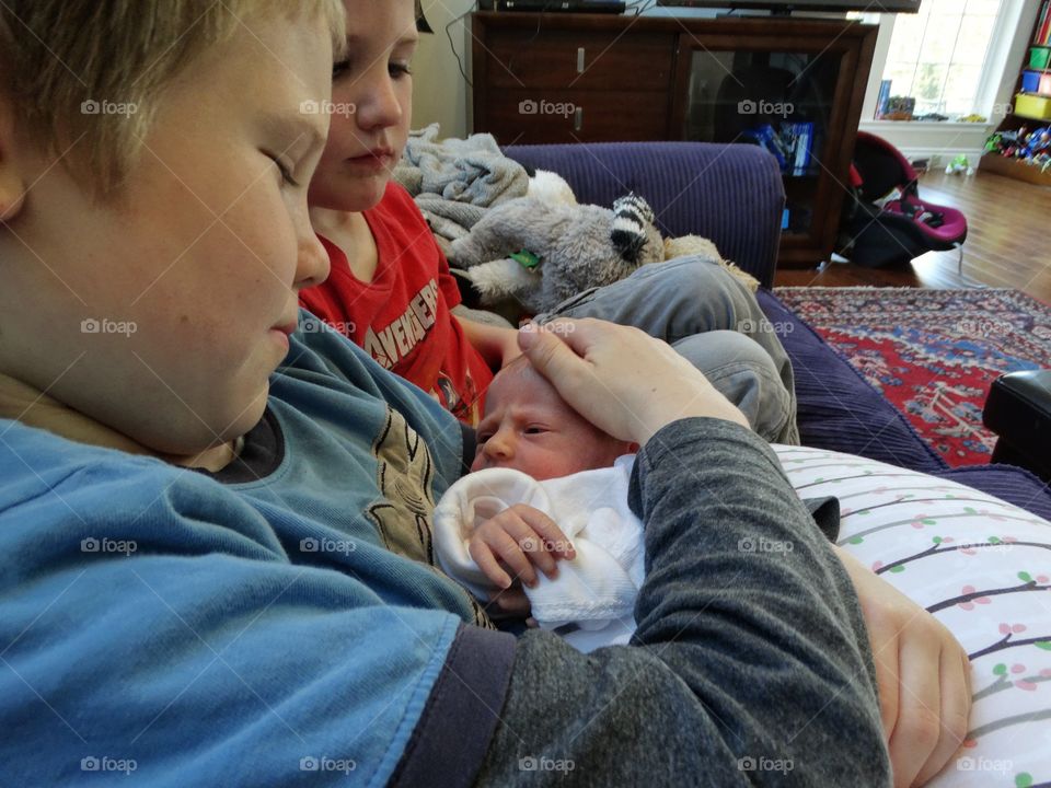 Brothers Holding Their Newborn Baby Sister