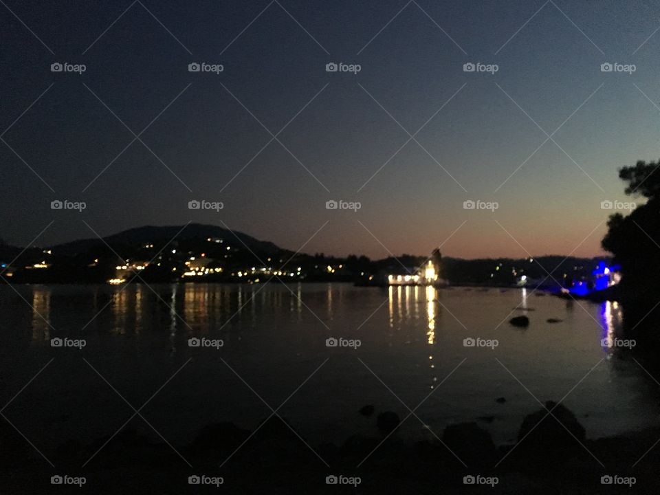 Corfu in the night time with the ocean with a amazing view while in the right of the photo is the sunset and on the left is the night. Calming photo and very beautiful 