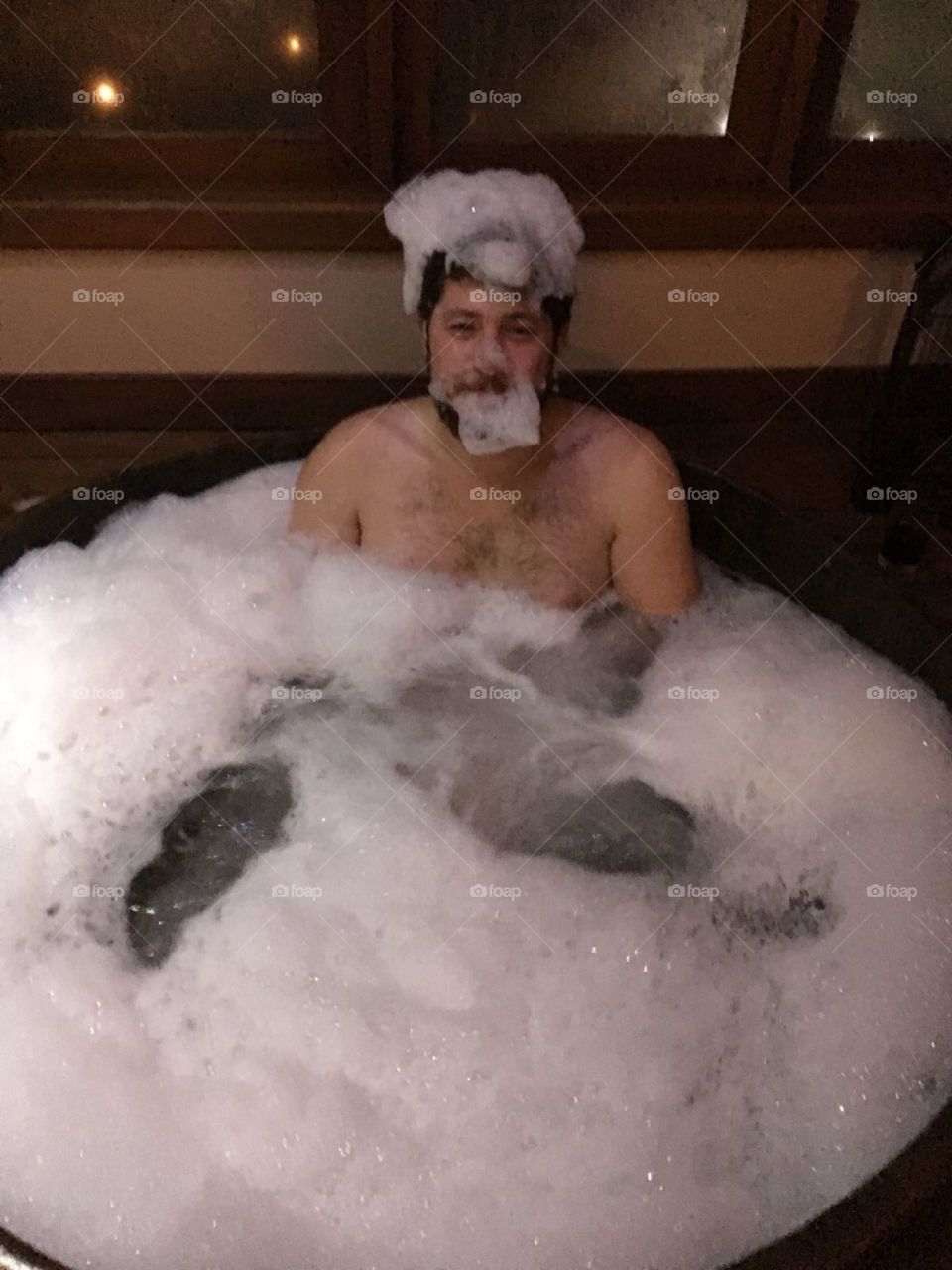 Homem se divertindo tomando banho em banheira com espuma no rosto