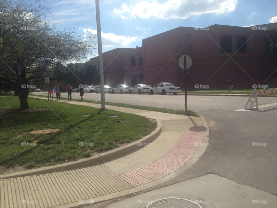 Police cars lined up on a campus street that has been closed with a barricade.