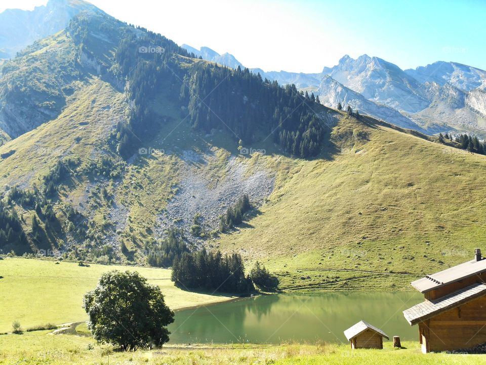Des chalets devant un lac au creux de la montagne