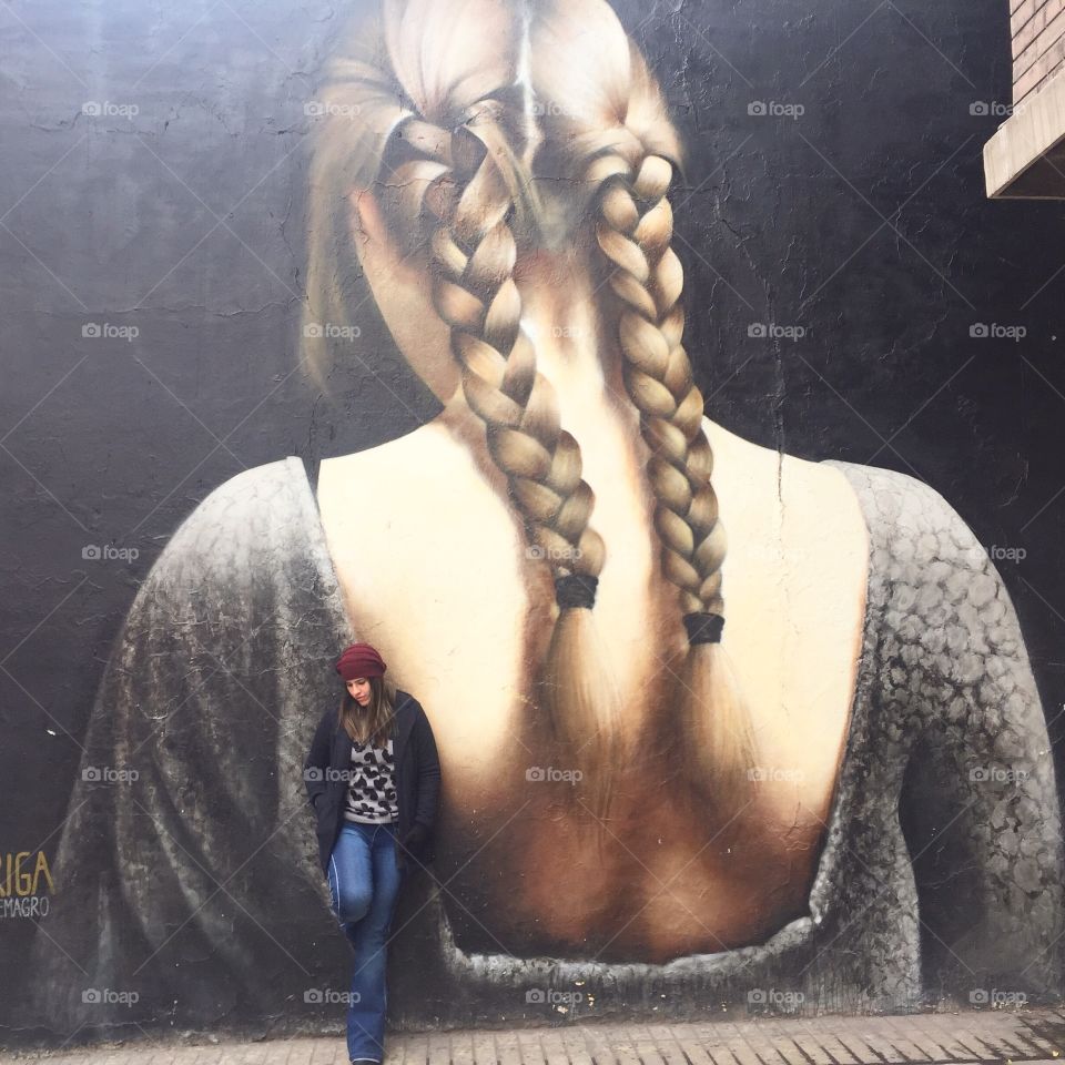 Pretty woman standing near printed wall