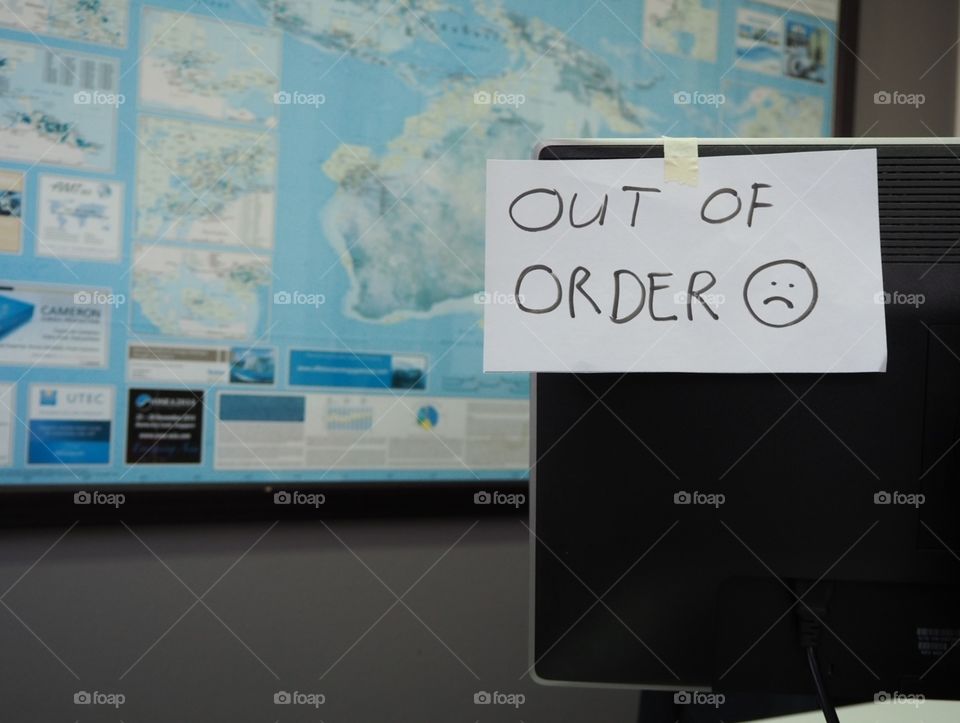 A computer monitor with a note that reads out of order.