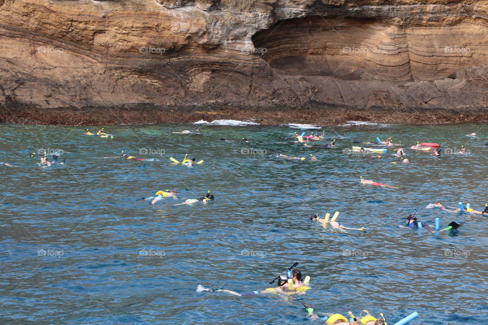 Snorkelling by the reef , colourful equipment , crowds 