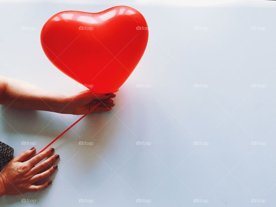 Hands with red heart shaped balloon