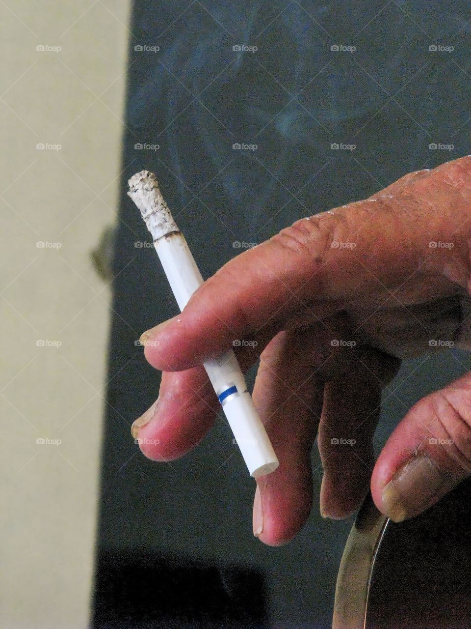 Close-up of man holding cigarette and smoking