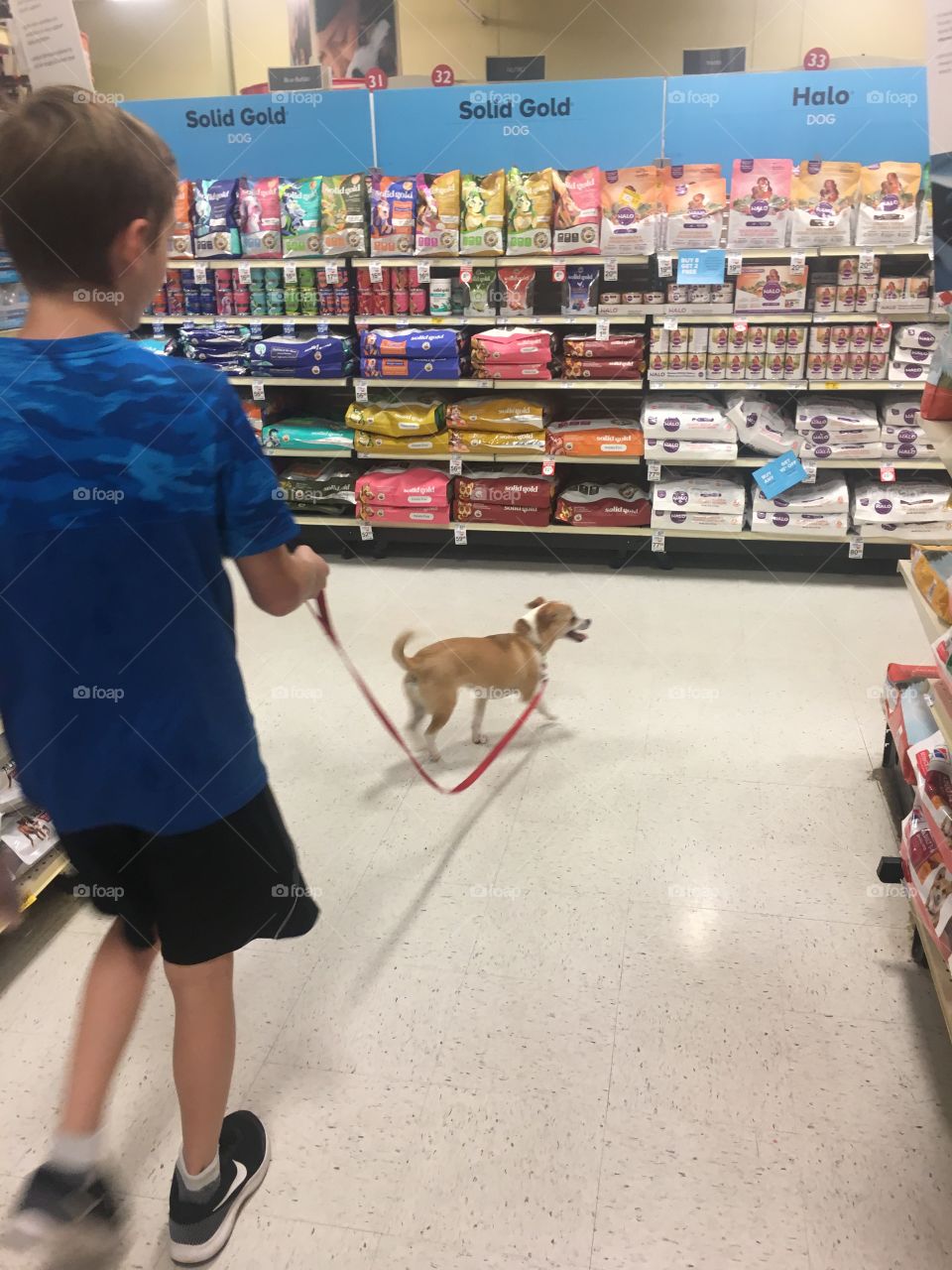 A boy and his dog race through a shopping center looking for goodies and treats. 
