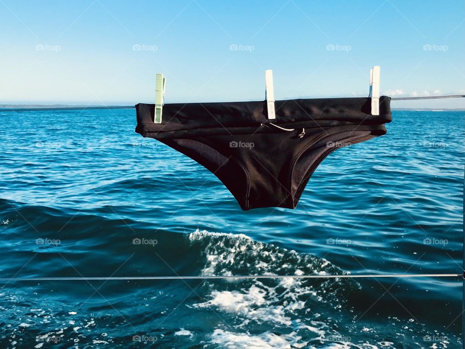 a black swim trunks stretched out on the side of a sailboat