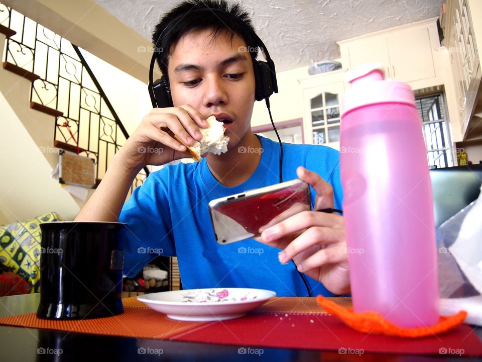 young teen eating snack while watching on a mobile device