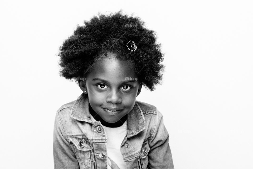 Black-and-white photograph of a young African-American girl cheerfully looking into camera.