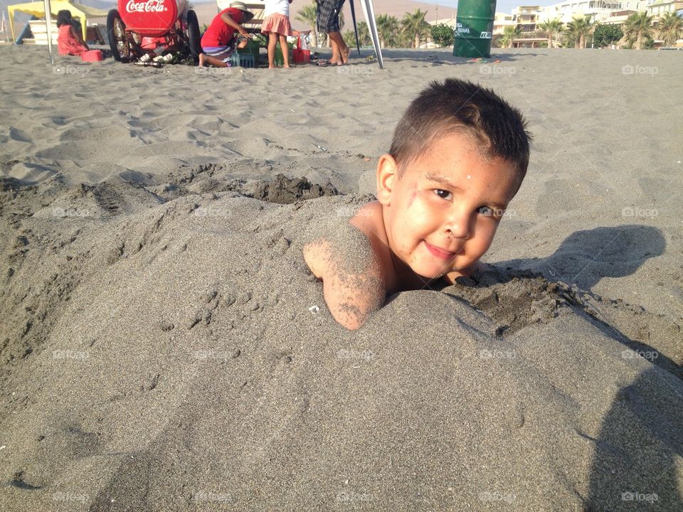 Boy in the sand . Boy at the beach playing in the sand getting buried 